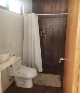 W łazience znajduje się biała toaleta i prysznic. w obiekcie Departamento cómodo y hermoso a mts de la playa w mieście San Crisanto