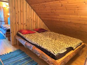a bed in a wooden cabin with two red pillows at Väike Kuu peamaja in Myza Kastre