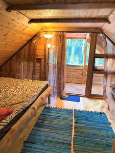 a bedroom in a log cabin with a bed and a rug at Väike Kuu peamaja in Myza Kastre
