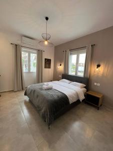 a bedroom with a large bed and two windows at Elefsinian Mysteries Apartments in Elefsina