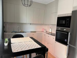 eine Küche mit weißen Schränken und einem Tisch darin in der Unterkunft Haga 1 bedroom Apartment in Stockholm