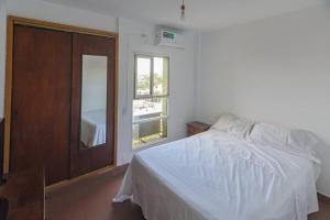 1 dormitorio con cama blanca y ventana en Departamento en Santiago del Estero en Santiago del Estero