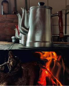 a metal tea kettle sitting on top of a fire at Pousada do Zezé in Bueno Brandão