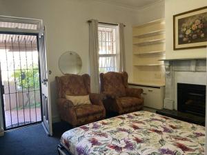 um quarto com uma cama, uma cadeira e uma lareira em Carolyn's Cottage em Adelaide