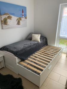 białe łóżko w pokoju ze zdjęciem latarni morskiej w obiekcie Apartment Sonnenrauschen w mieście Emden