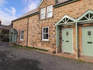 a brick house with green doors on a street at Willow Cottage in Alnmouth