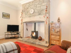a living room with a fireplace and a tv at Willow Cottage in Alnmouth