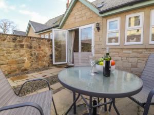 a table with a bottle of wine and a bowl of fruit on a patio at Willow Cottage in Alnmouth