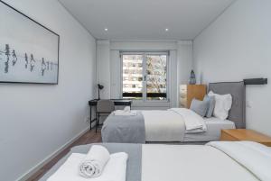 a white bedroom with two beds and a window at Coastal Charm by LovelyStay in Oeiras