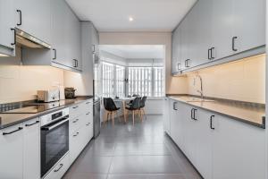 uma cozinha com armários brancos e electrodomésticos pretos em Coastal Charm by LovelyStay em Oeiras