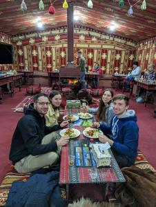瓦迪拉姆的住宿－Bedouin host camp& with tour，一群坐在餐桌上吃食物的人
