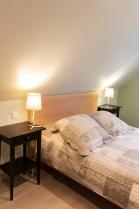 ein Schlafzimmer mit einem Bett und einem Tisch mit zwei Lampen in der Unterkunft Les Granges De Jadis d'Alsace in Holtzwihr