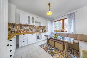 a kitchen with white cabinets and a table and a couch at Apartmány Kašper in Levoča