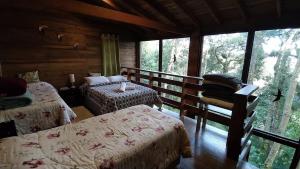 1 dormitorio con 2 camas en una cabaña de madera en Chalé dos Tucanos- Parede de vidro com linda vista, en Campos do Jordão