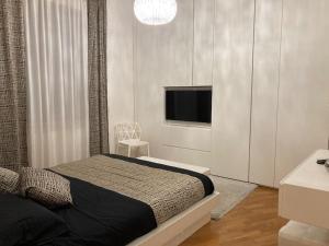 a bedroom with a bed and a flat screen tv at Thesan Lodge, chic & modern design apartment in Grosseto