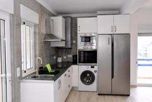 a kitchen with white cabinets and a stainless steel refrigerator at Casa Azul in Monte Gordo +60 photos