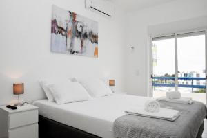 a white bedroom with a large bed and a window at Casa Azul in Monte Gordo