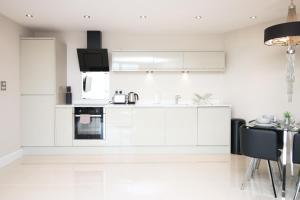 a white kitchen with white cabinets and a table at The Skyline - LONG STAY OFFER - Luxury Flat w/Designated Parking in Cardiff