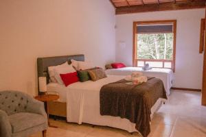 a bedroom with two beds and a chair and a window at Villa Rica Pousada Boutique in Brumadinho