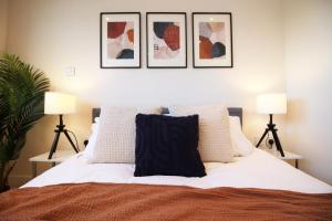 a bedroom with a bed with four pictures on the wall at The Skyline - LONG STAY OFFER - Luxury Flat w/Designated Parking in Cardiff