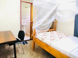 1 dormitorio con cama, escritorio y silla en Home from home en Mbale