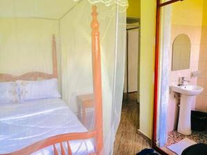 a bedroom with a canopy bed and a sink at Home from home in Mbale