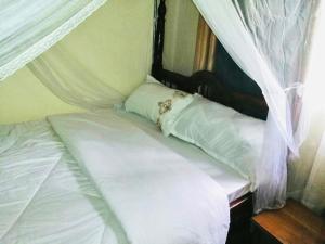 Cama en habitación con cortinas blancas en Home from home, en Mbale