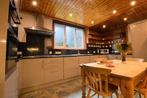 uma cozinha com uma mesa e um tecto de madeira em Cologin Farmhouse em Oban