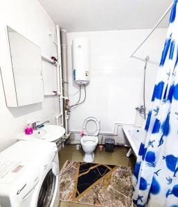 y baño con aseo, lavabo y lavadora. en Уютные апартаменты прям в центре города, en Pavlodar
