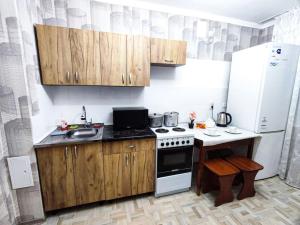una pequeña cocina con fogones y nevera. en Уютные апартаменты прям в центре города, en Pavlodar