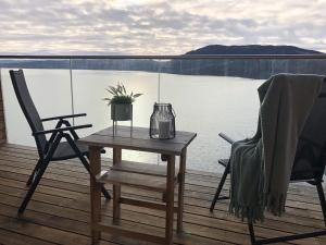 una mesa y 2 sillas en una terraza con vistas al agua en MJOS TOWER Suite - Lovely lake view en Brumunddalen