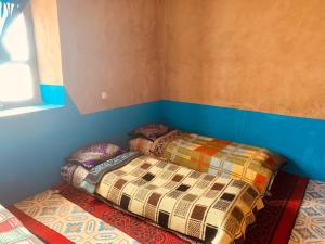 2 camas en una esquina de una habitación en Desert Backpackers hostel, en Merzouga