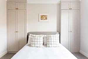 a bedroom with a bed with white walls and white cabinets at Lovely Camberwell House in London