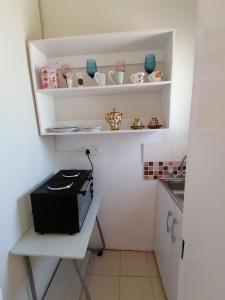 a small kitchen with white walls and white shelves at Country Block in Gaborone