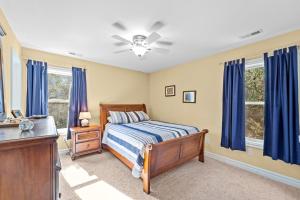 1 dormitorio con cortinas azules, 1 cama y vestidor en The Sandlot, en Southern Shores