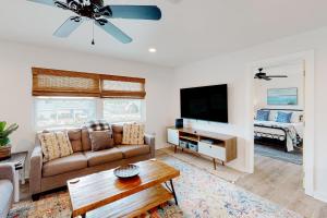 a living room with a couch and a tv at The Beach Sunflower in Pensacola Beach