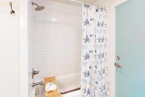 a bathroom with a blue and white shower curtain at The Beach Sunflower in Pensacola Beach +33 photos