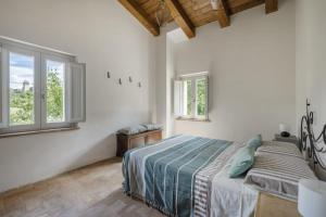 una camera bianca con un letto e due finestre di Piano del Mulino a Orvieto