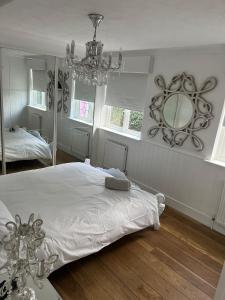 Dormitorio con cama con espejo y lámpara de araña en Beautiful Little Bungalow, Indoor Fireplace, & Bar en Ash