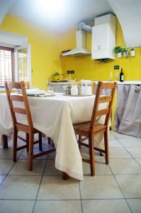 een keuken met een tafel met stoelen en gele muren bij QuickHome La Ninfea in Viverone