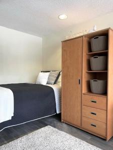 a bedroom with a bed and a wooden cabinet at Residence & Conference Centre - Sarnia in Sarnia