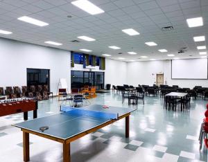 um quarto com uma mesa de pingue-pongue e mesas e cadeiras em Residence & Conference Centre - Sarnia em Sarnia
