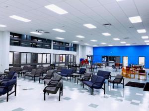 an empty waiting room with blue chairs and tables at Residence & Conference Centre - Sarnia in Sarnia