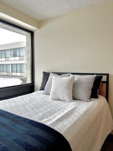 een slaapkamer met een bed en een groot raam bij Residence & Conference Centre - Sarnia in Sarnia