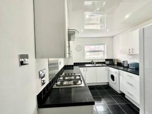 a kitchen with white cabinets and a stove top oven at Liverpool Getaway Home! in Liverpool