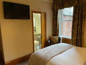 a bedroom with a bed and a mirror and a window at Brooklands Guest House in Penrith