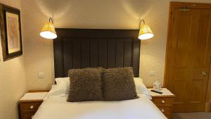 a bedroom with a large bed with two lights at Brooklands Guest House in Penrith