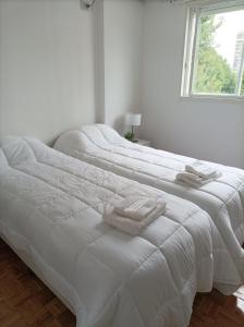 2 witte bedden in een witte slaapkamer met een raam bij Beños in Buenos Aires