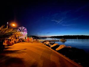 a group of people sitting on a dock by the water at night at Apartment Deluxe IM in Medulin