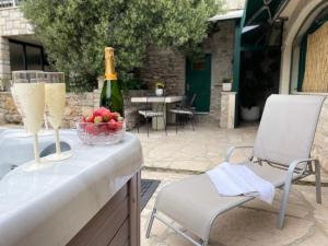 a table with a bottle of champagne and a bowl of fruit at Vacation House Marin with Jacuzzi - Bol, Brač in Bol